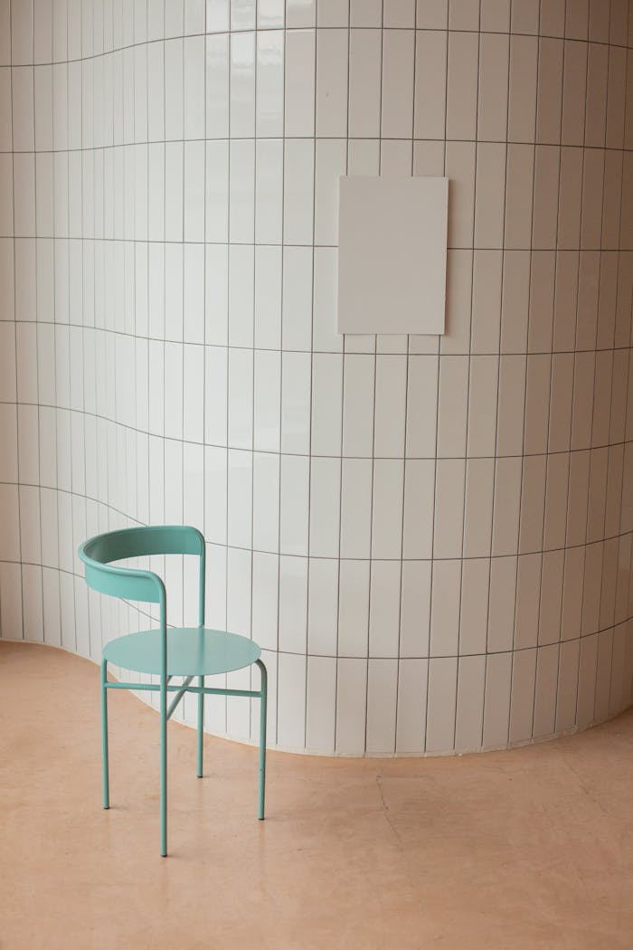 Chair near wall with ceramic tile and white placard